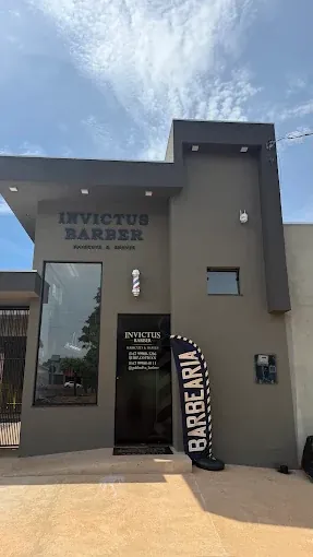 Fachada da Invictus Barber, com a placa na parede e o poste de barbeiro ao lado da porta