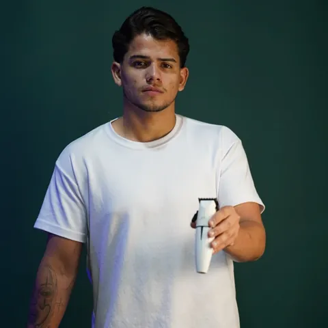 Marco, barbeiro da Invictus, segurando uma máquina de corte
